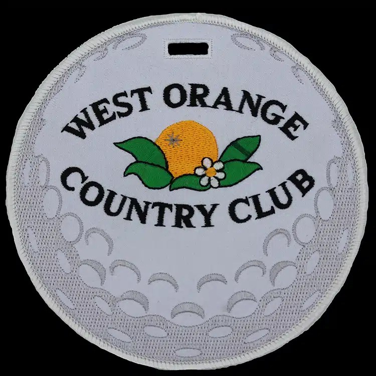 Round embroidered luggage tag styled as a golf ball for West Orange Country Club, white on white, an example of Patchworks USA's finished work.