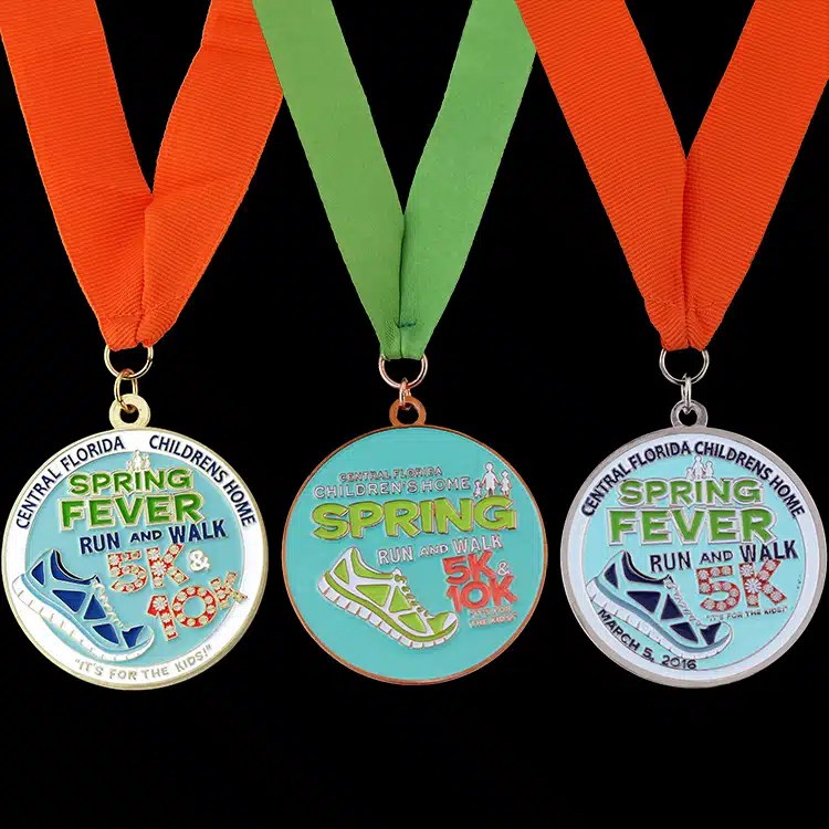 Three Spring Fever run and walk finisher medals on orange and green neck ribbons
