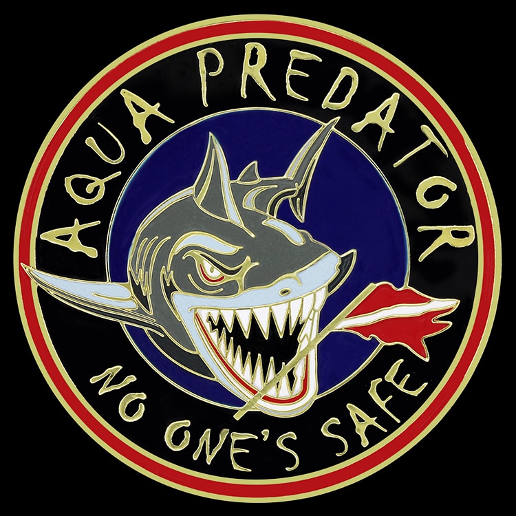 Round coin with a red and gold rim, a grinning grey shark on a navy enamel field and raised gold lettering around the edge.
