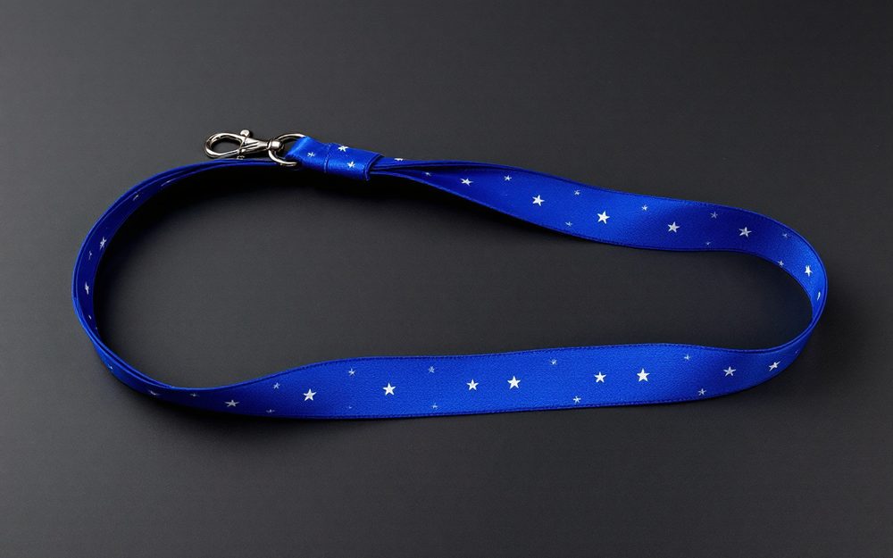 Royal blue nylon lanyard with a glossy satin finish and a white star print, laid in a loop with a silver swivel J-hook.