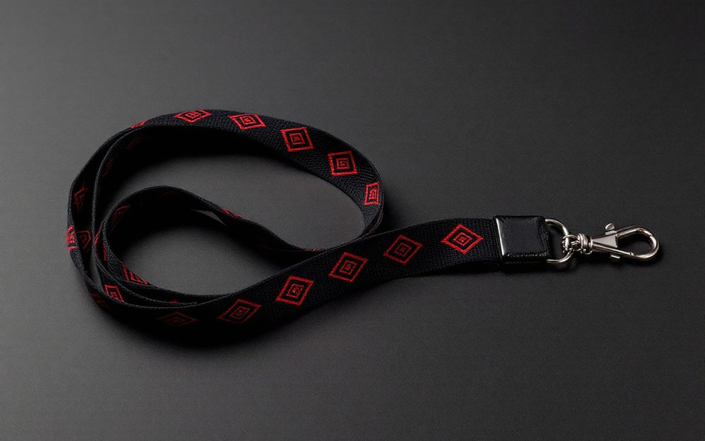Black jacquard woven lanyard with red diamond motifs woven into the strap, finished with a silver lobster claw clip.