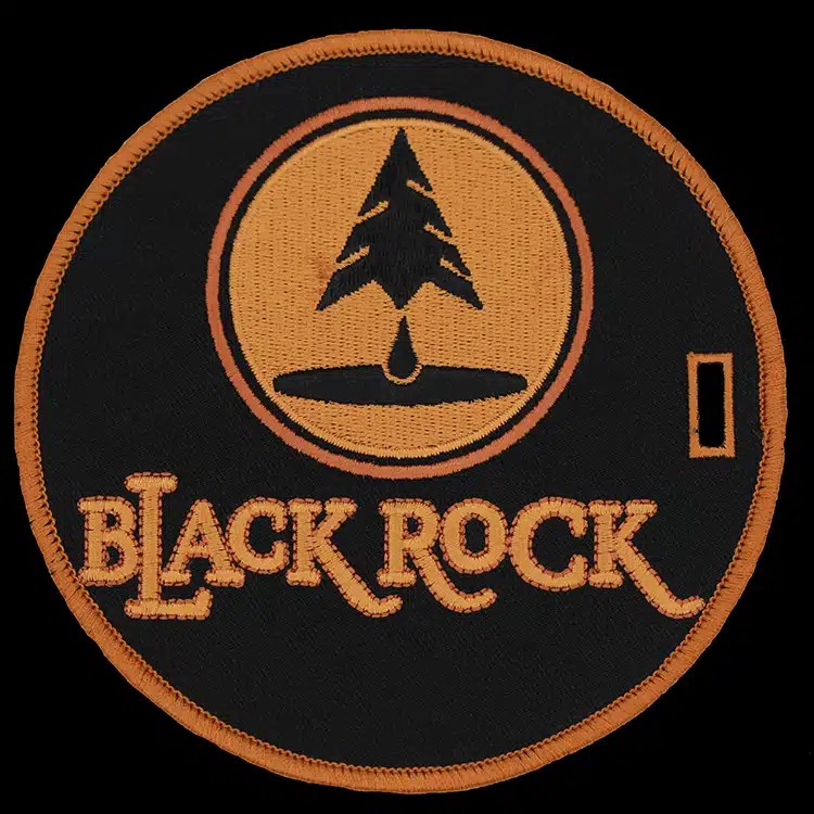 Round embroidered luggage tag with a pine tree logo in orange on black and a strap slot, made for Black Rock.