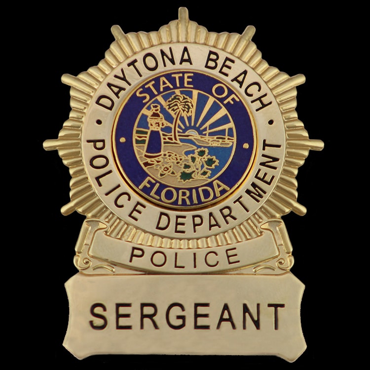 Gold tone metal badge with a blue enamel seal, an example of the plating and enamel finishes also used on struck medals.