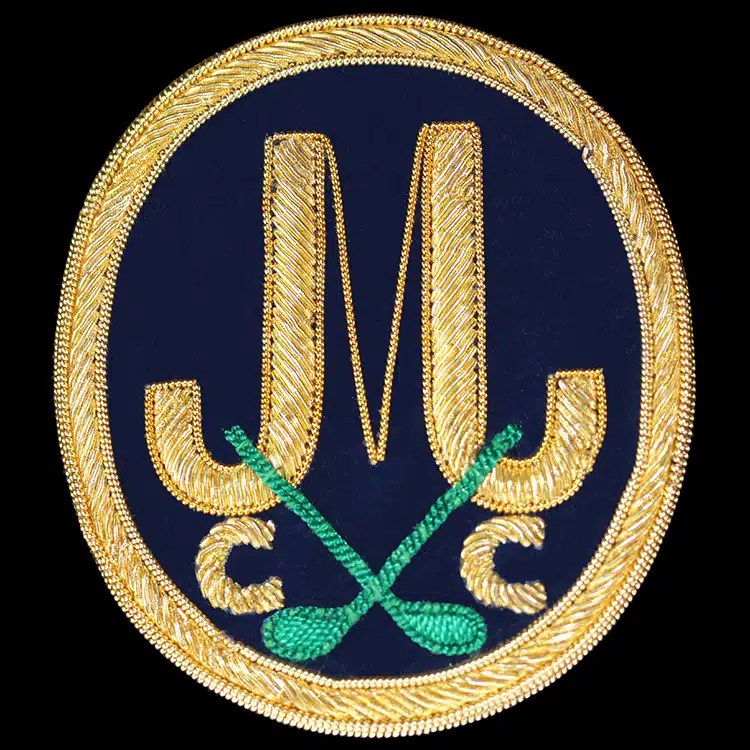 Hand embroidered gold bullion golf club crest with crossed clubs on navy.